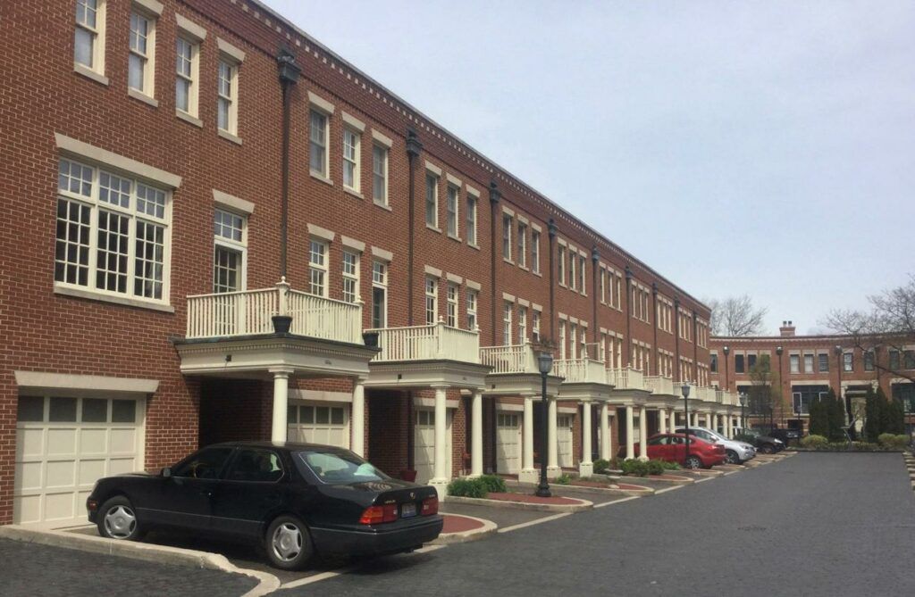 A row of brick buildings with cars parked in front of them.