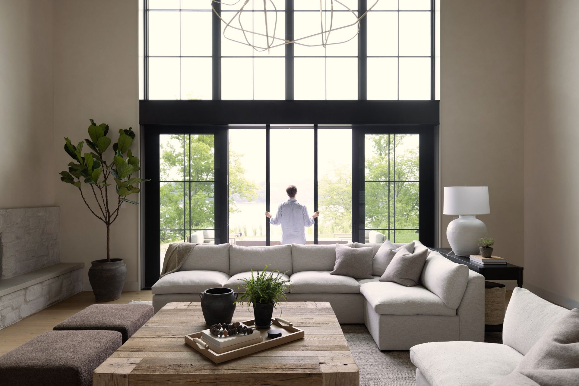 A man is standing in a living room looking out a window.
