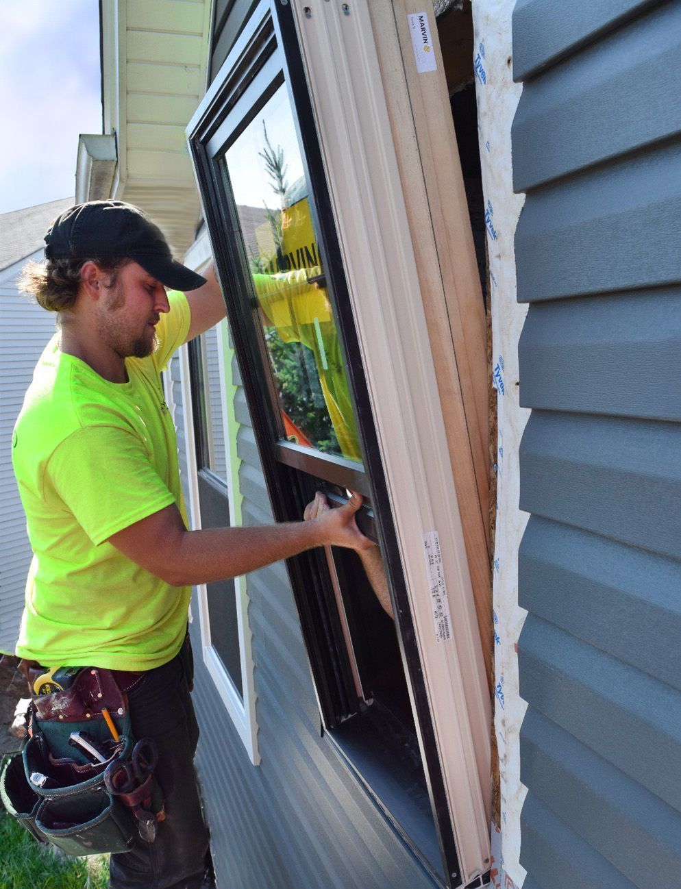A man is installing a window on the side of a house