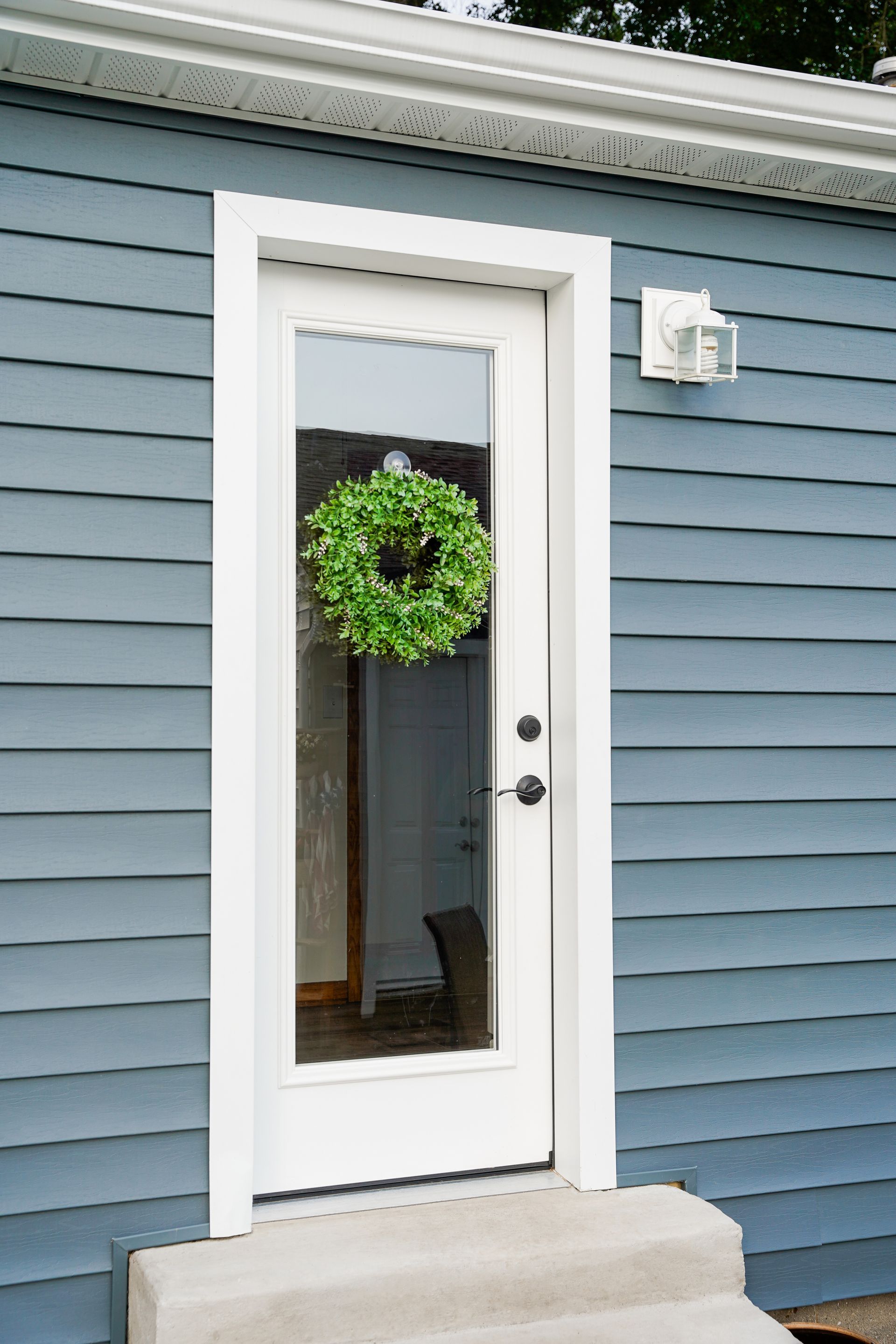 A blue house with a white door and a wreath on it.
