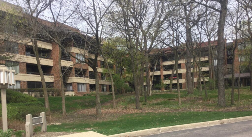 A large apartment building with a lot of trees in front of it.