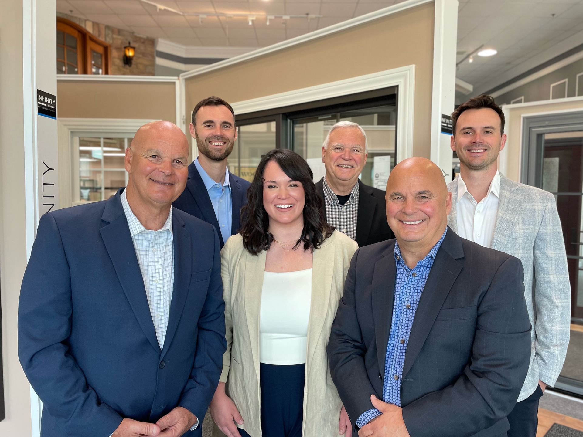 Six people, business group smiling in showroom.