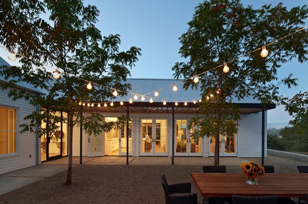 A white house with a wooden table and chairs in front of it
