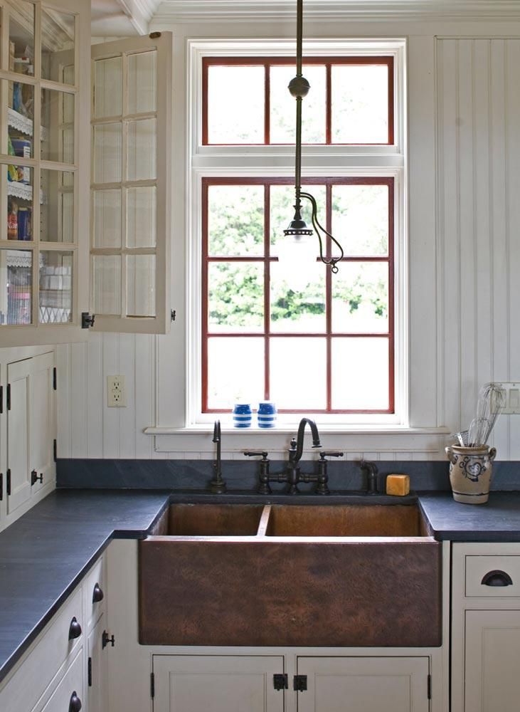 A kitchen with a copper sink and a window