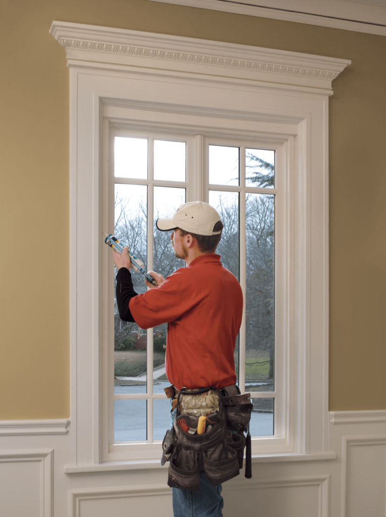 A man is sealing a window with sealant.