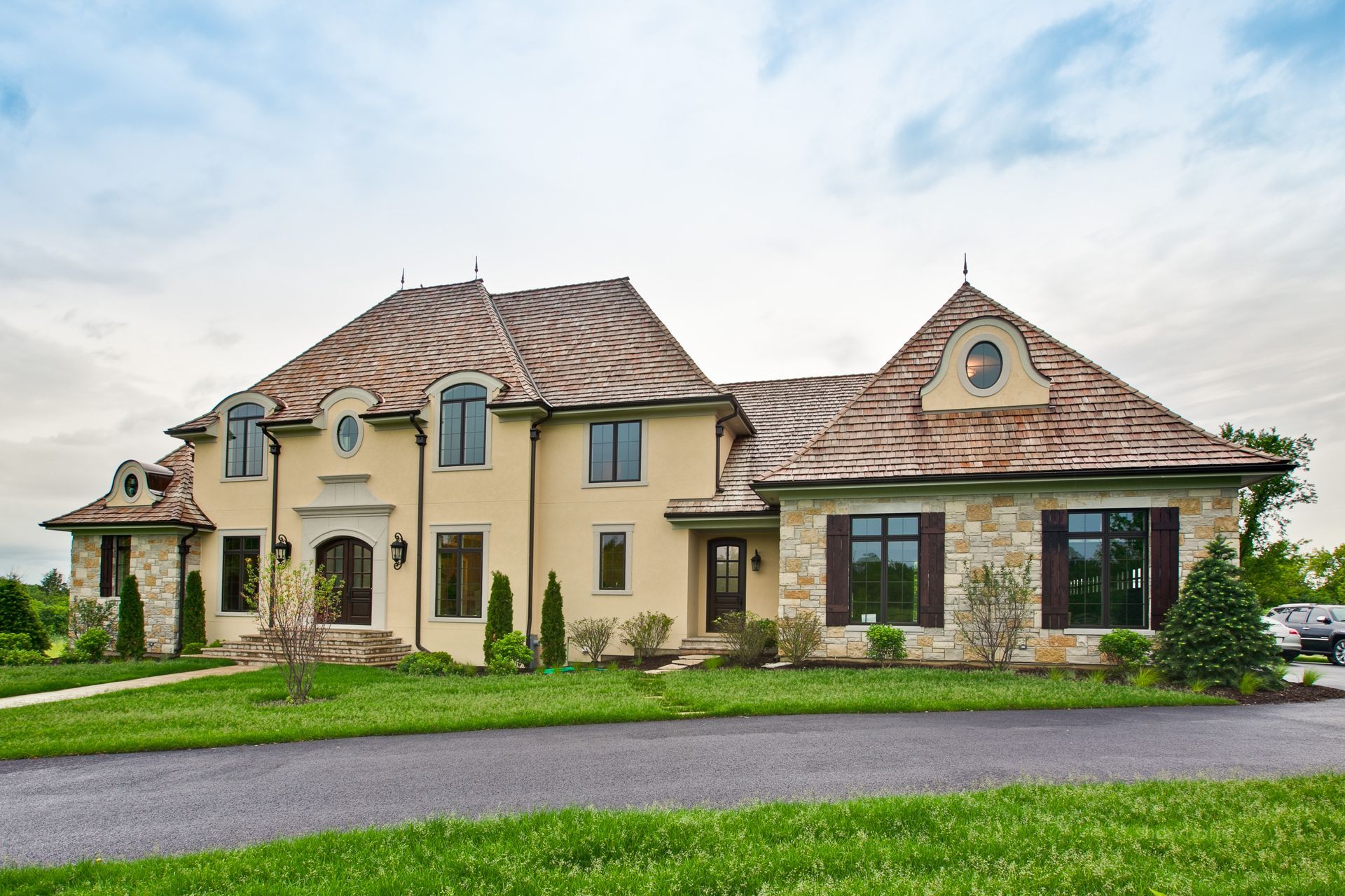 A large house with a lot of windows is sitting on top of a lush green field.