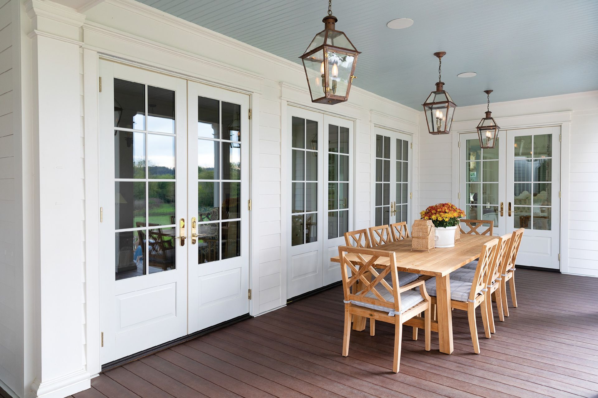 A patio with a table and chairs and lanterns hanging from the ceiling