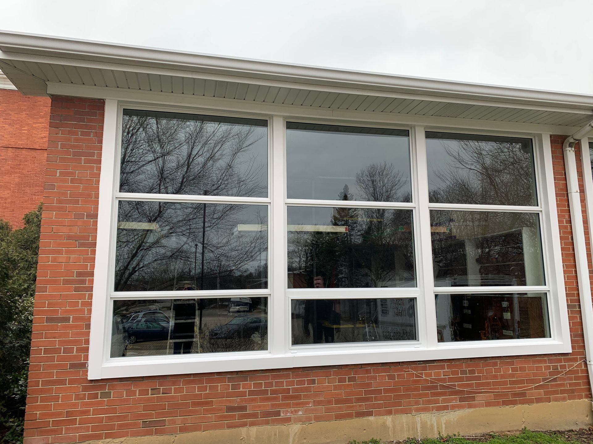 Brick building exterior with large multi-pane windows; cloudy day.