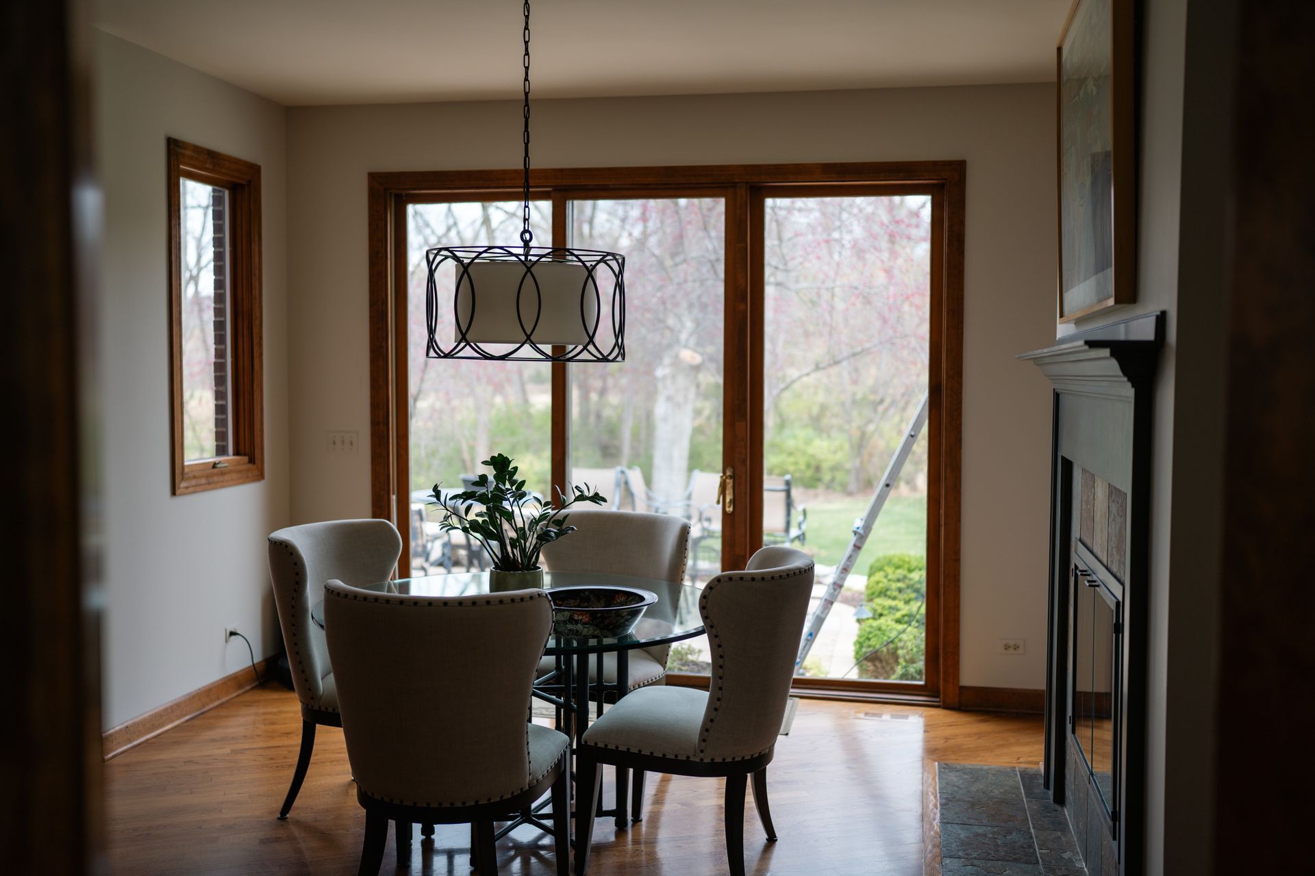 Dining room with a table and four chairs near a large window, a chandelier hangs above.