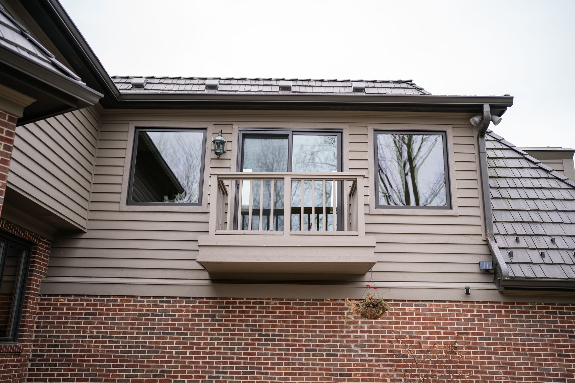 Exterior view of a building with a small balcony, windows, and brick and wood siding.