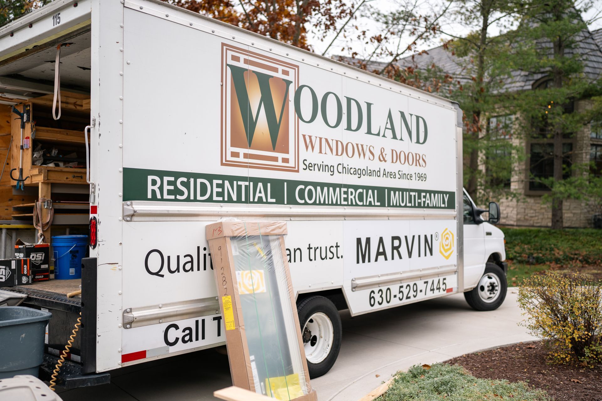 Woodland Windows & Doors truck parked in front of a house, with a window leaning against it.