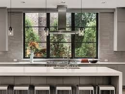 Modern kitchen with large window overlooking greenery, island with stools, and pendant lights.