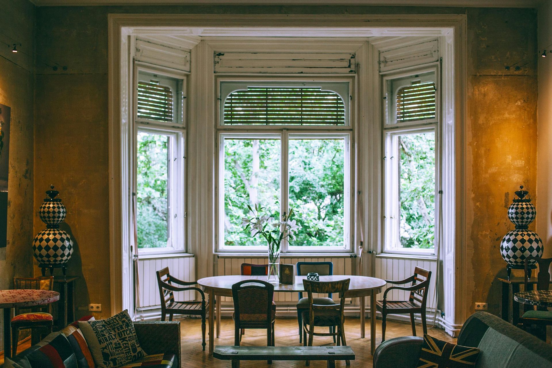 Elegant room with large bay windows, wooden chairs, and a table overlooking greenery outside