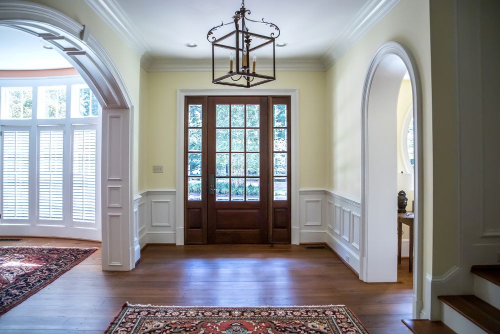 A large empty hallway with a wooden door and a rug.