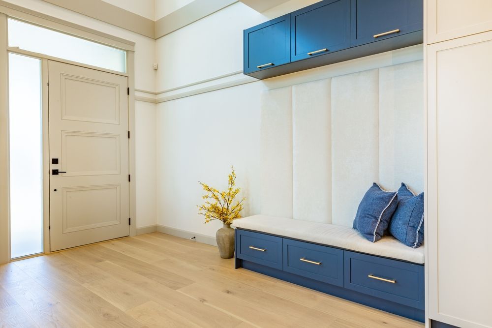 There is a bench in the hallway with blue cabinets.
