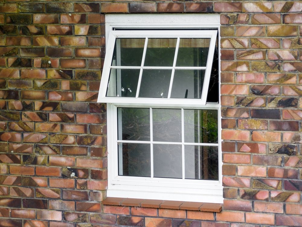 A white window is on a brick wall