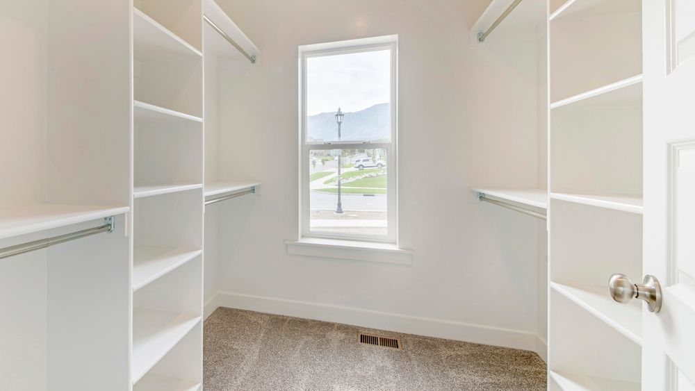 A walk in closet with lots of shelves and a window.