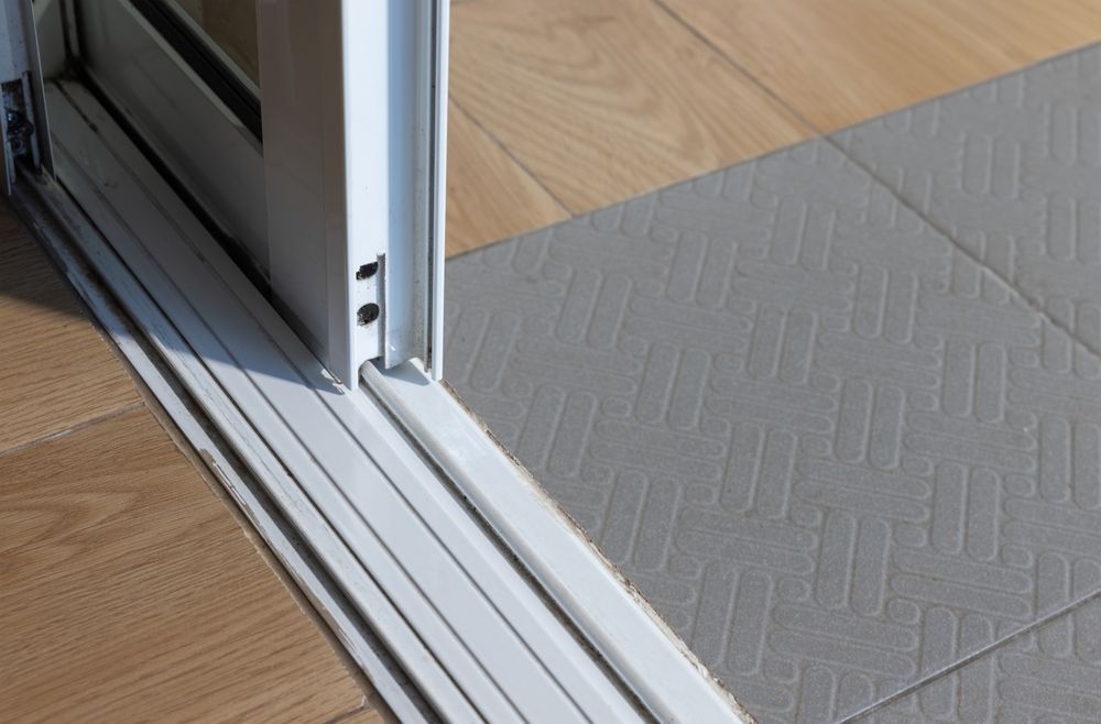 A close up of a sliding glass door on a wooden floor.