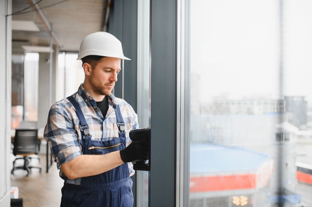 Worker in hard hat and gloves installing a glass window indoors