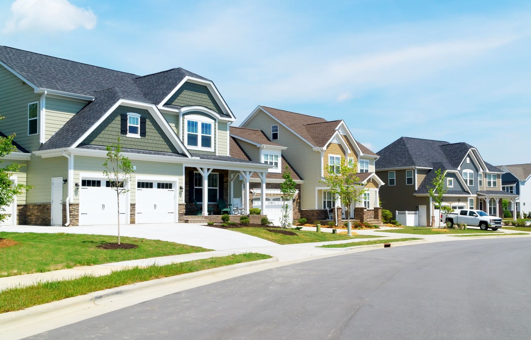 Row of modern houses on a sunny street, with various exterior colors and a blue sky.