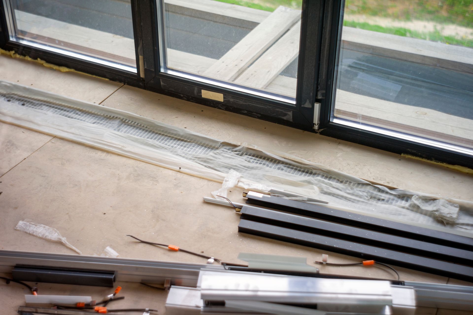 Window frame parts on floor; black frame next to large window.