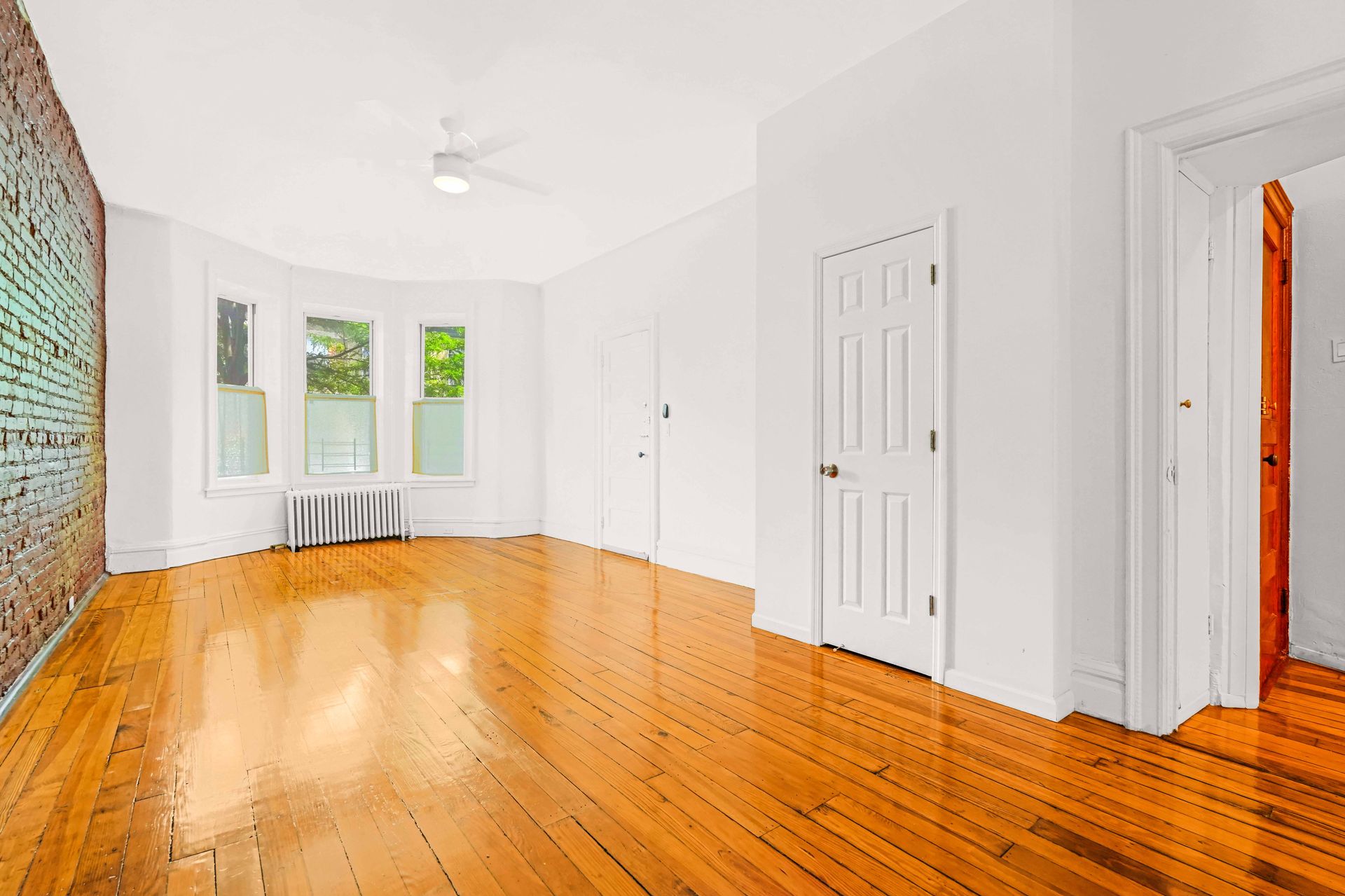 An empty living room with hardwood floors and white walls.