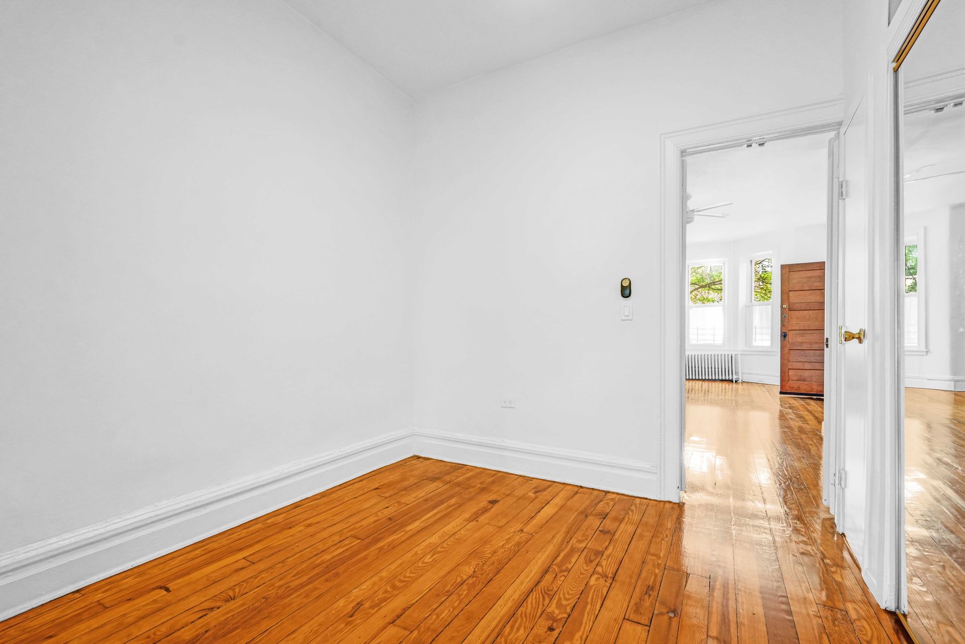 An empty room with hardwood floors and white walls.
