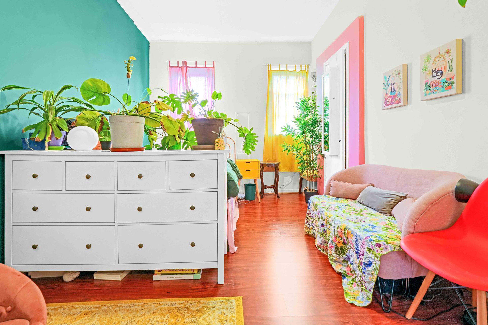 A living room with a pink couch and a white dresser