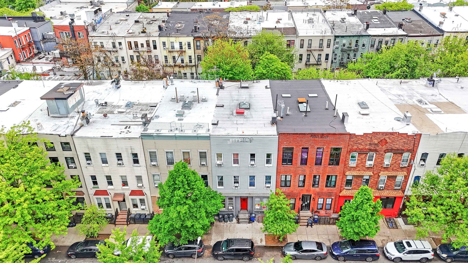 An aerial view of a row of buildings with cars parked in front of them.
