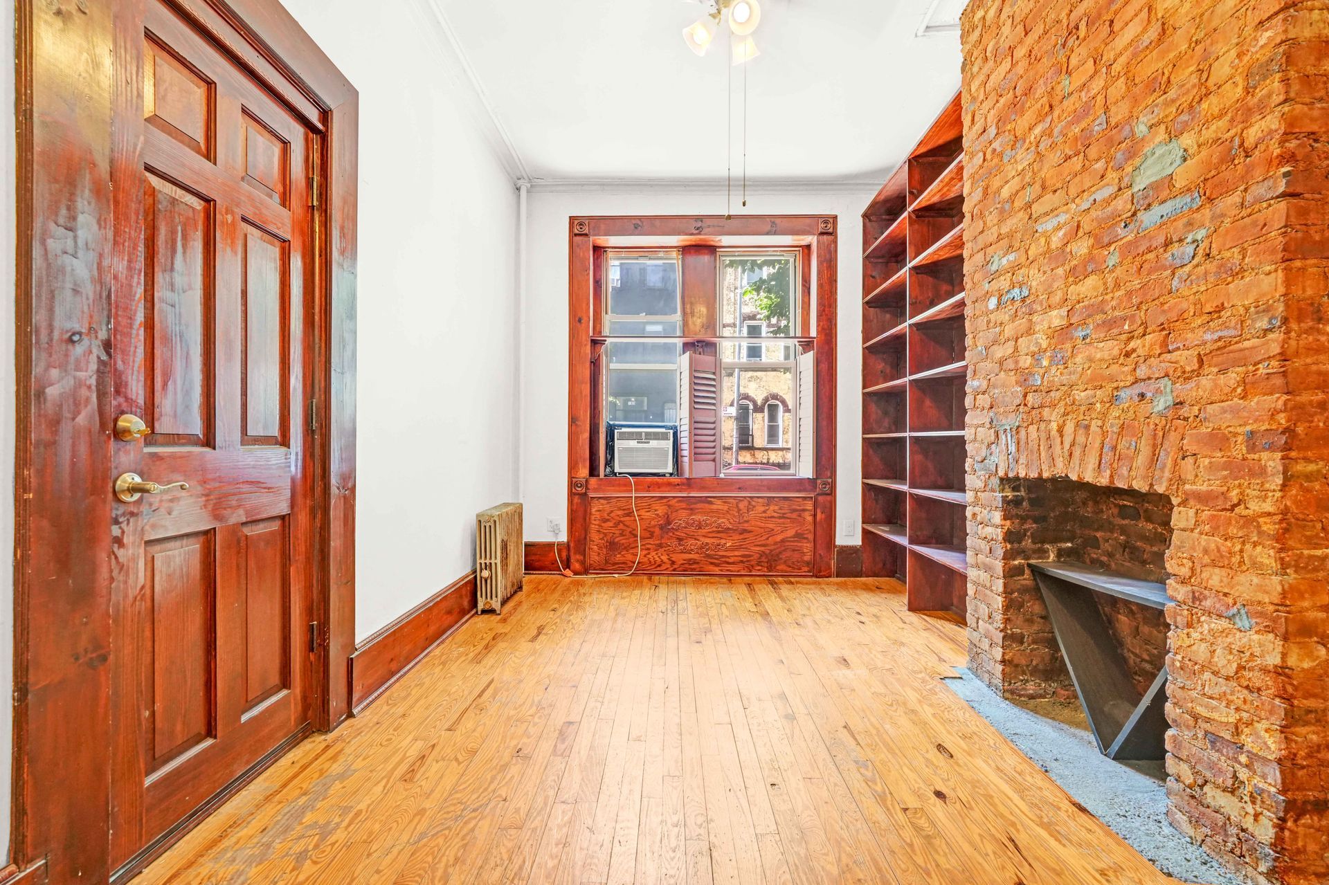 An empty room with hardwood floors and a brick fireplace.