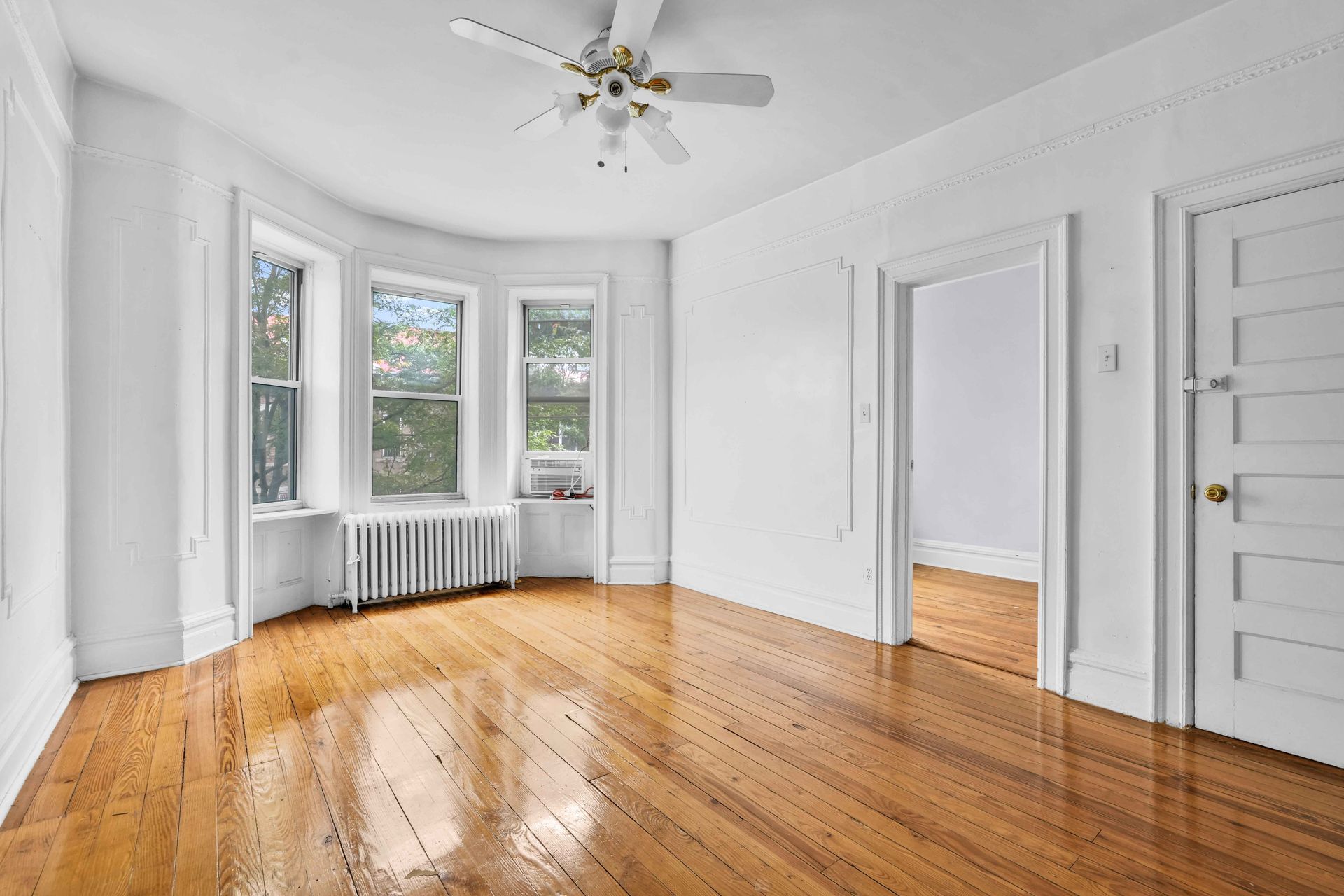An empty room with hardwood floors and a ceiling fan.