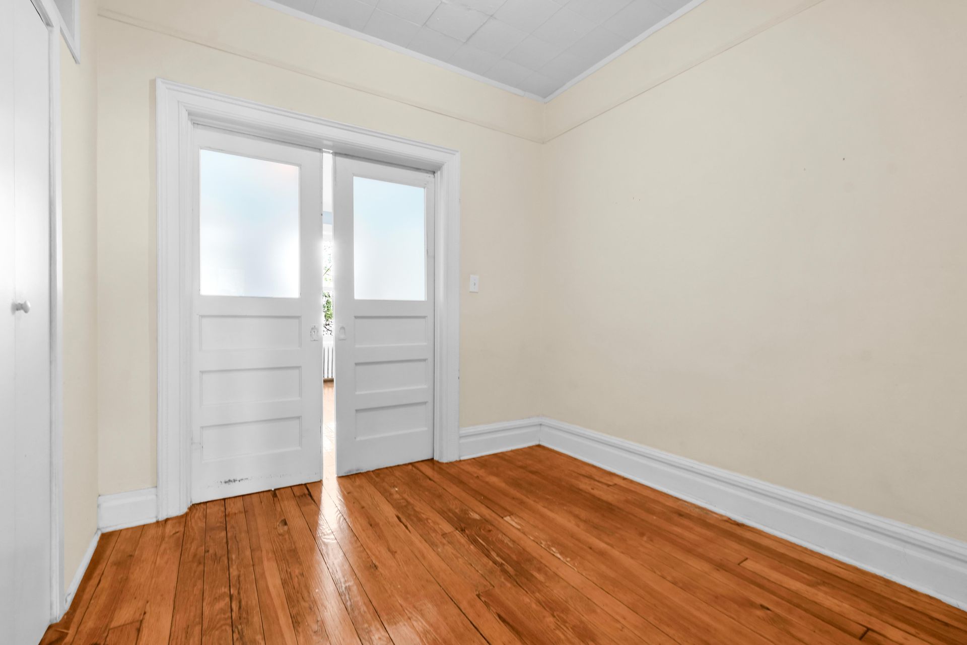 An empty room with hardwood floors and sliding glass doors.