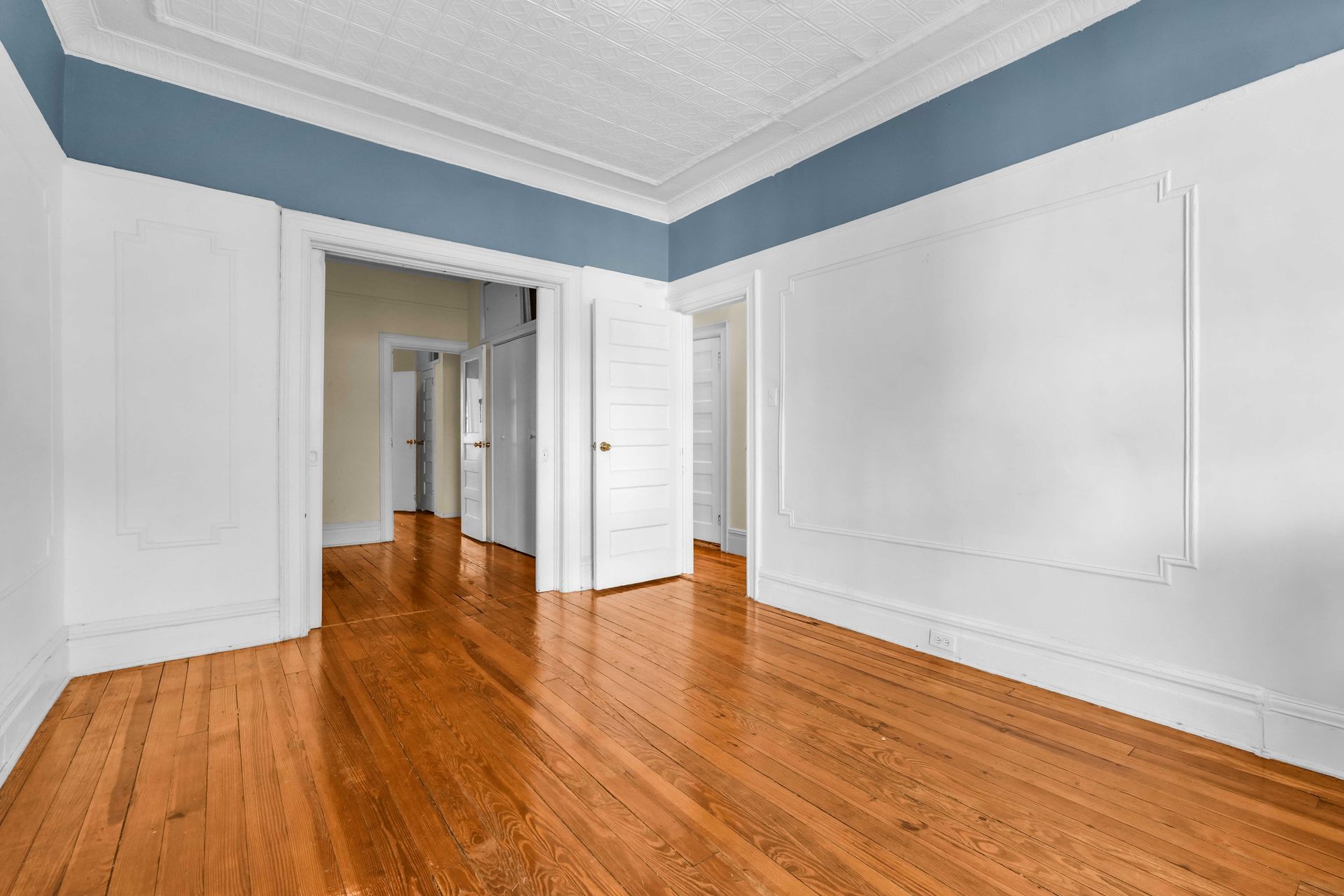 An empty room with hardwood floors and white walls.