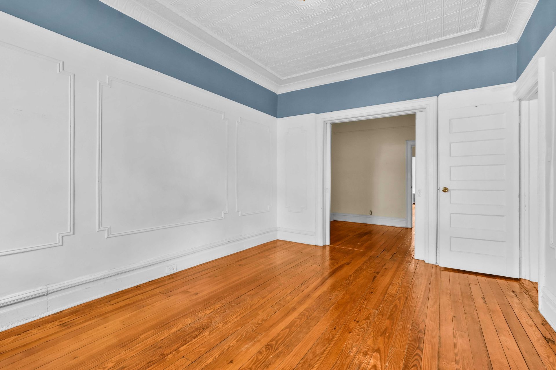An empty room with hardwood floors and white walls.