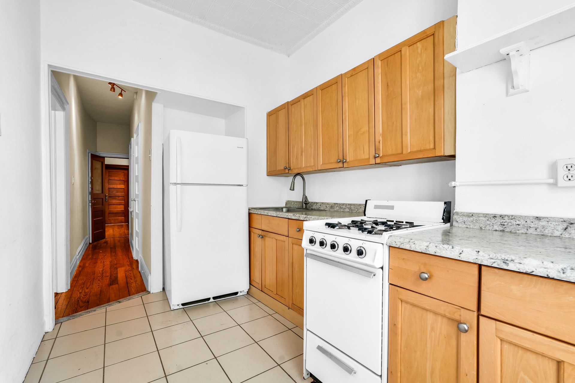 A kitchen with wooden cabinets and a white stove and refrigerator