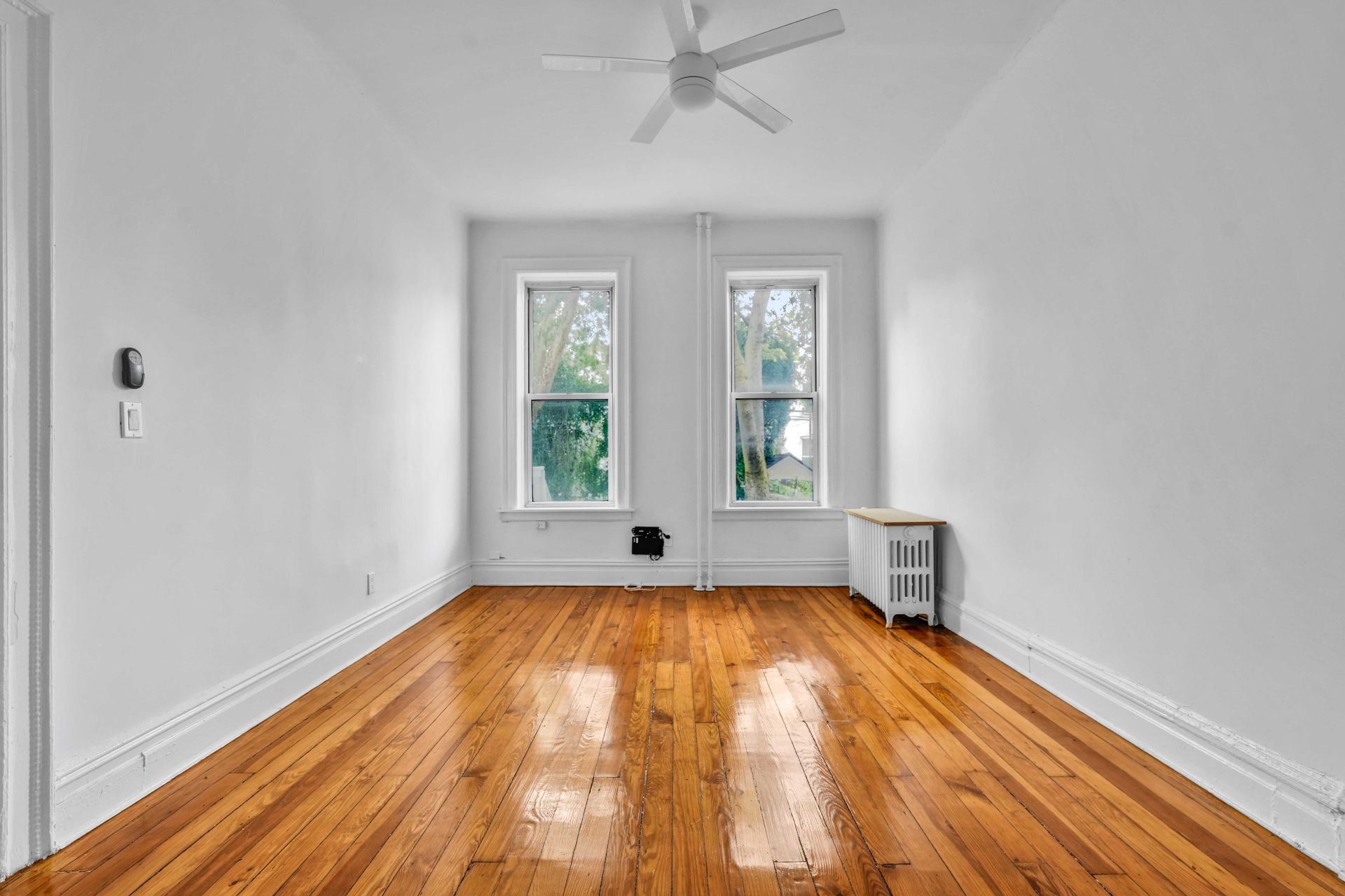An empty room with hardwood floors and a ceiling fan.