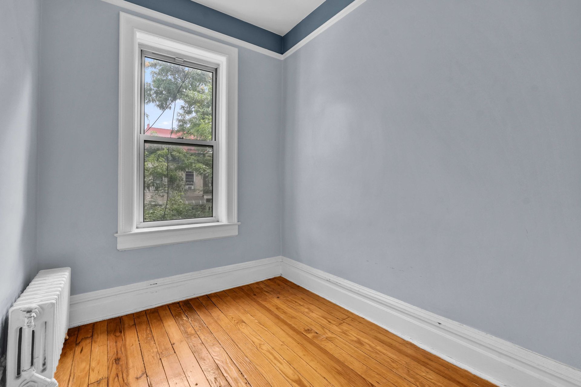 An empty room with hardwood floors and a window.