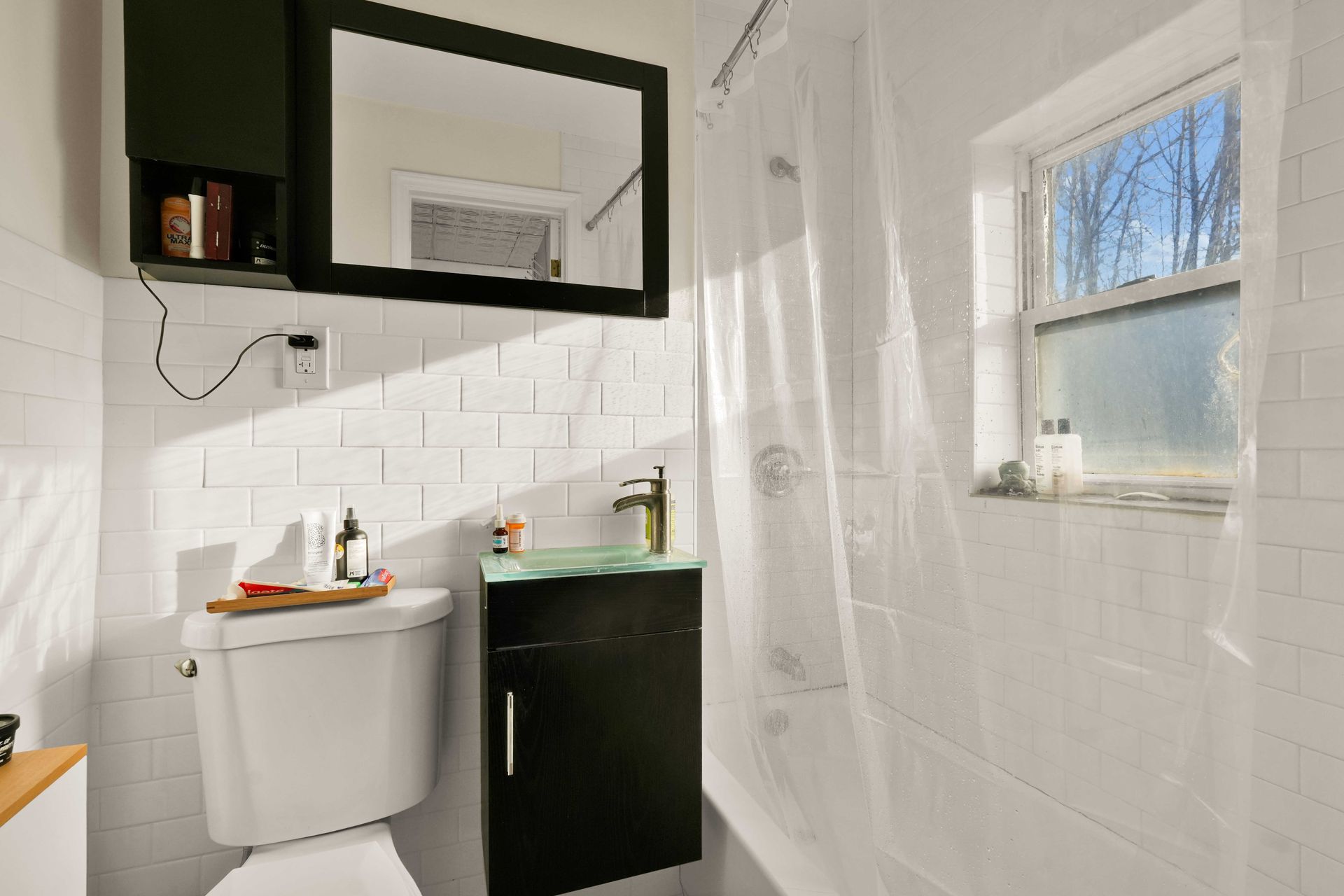 A bathroom with a toilet , sink , shower and mirror.