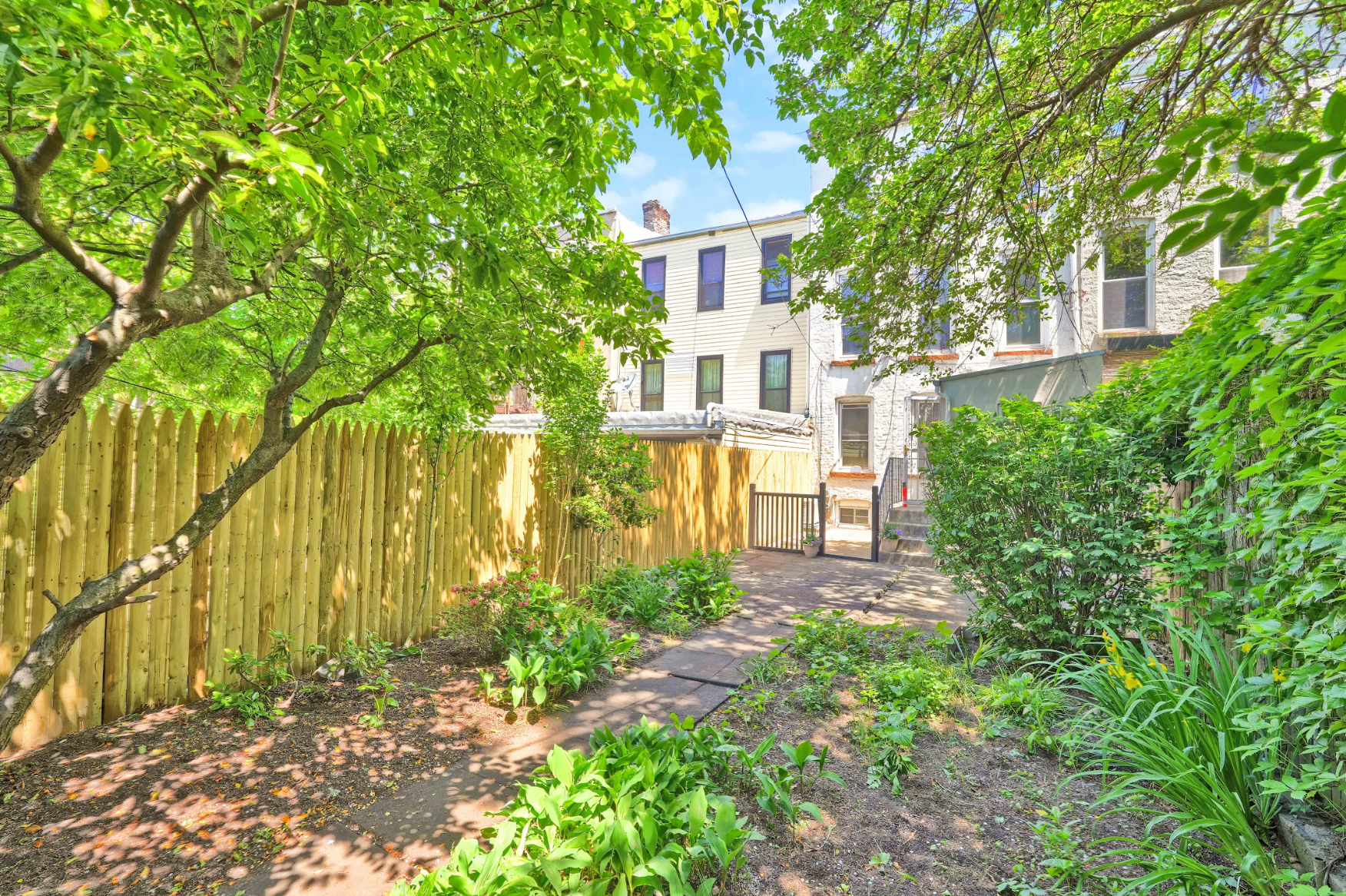 A backyard with a wooden fence and trees in front of a house.