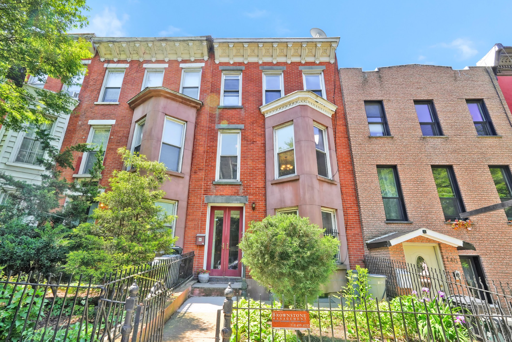 A brick building with a red door is for sale