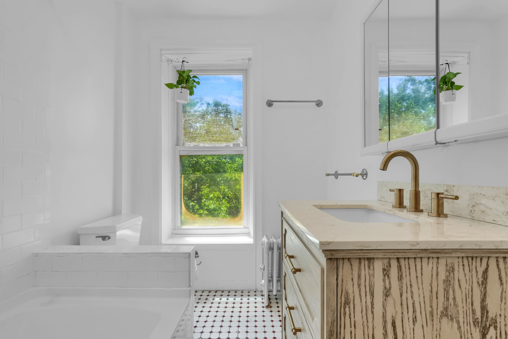 A bathroom with a sink , tub , mirror and window.