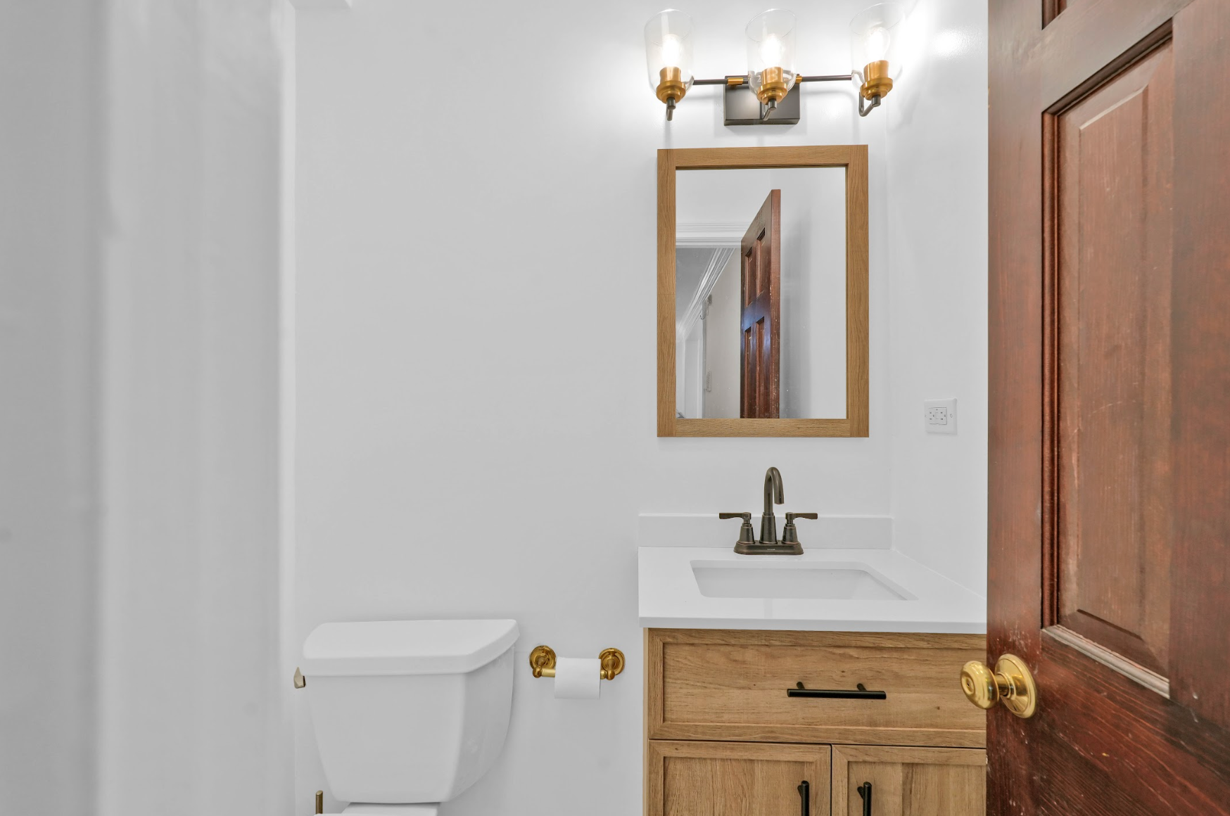 A bathroom with a toilet , sink and mirror.