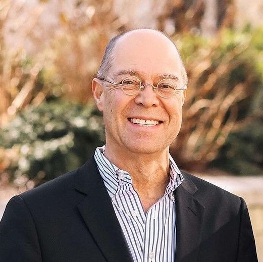 A man in a suit and striped shirt is smiling for the camera.