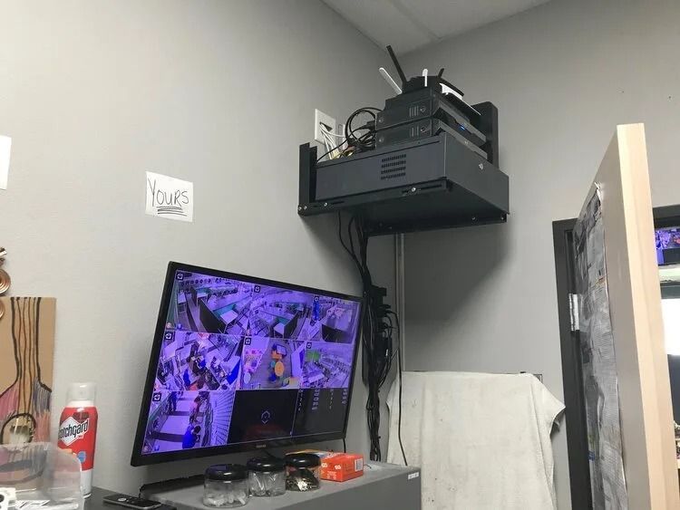 Small room with a tilted TV showing a purple game scene and a wall-mounted projector above it.