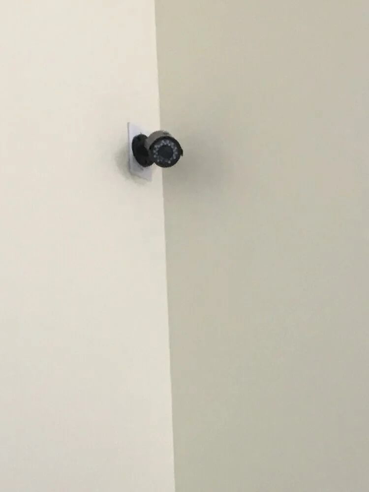 Black security camera mounted on a white corner wall