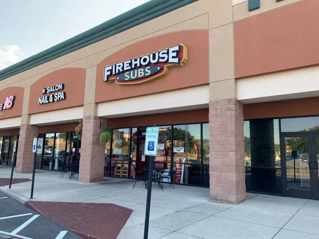 Firehouse Subs storefront in a shopping plaza with beige and brick exterior.