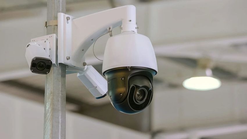 White security camera mounted on a ceiling bracket indoors