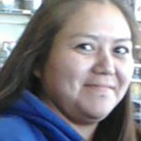 A woman in a blue hoodie is smiling for the camera.