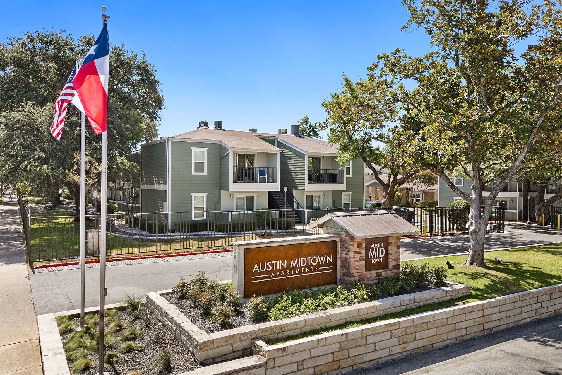 Austin Avenue apartment sign with U.S. and Texas flags in front of a residential building