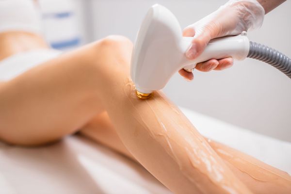 Leg being waxed with a handheld laser device in a spa treatment room